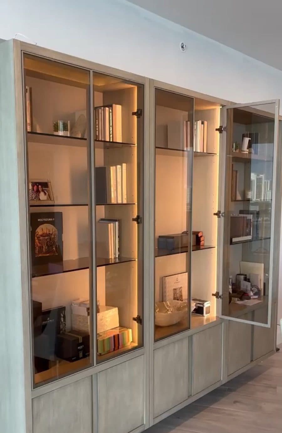 Built-in display wall with slim aluminum-framed glass doors and integrated lighting